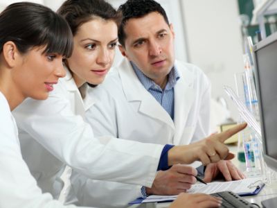 Drei Laboranten besprechen Ergebnisse am Monitor