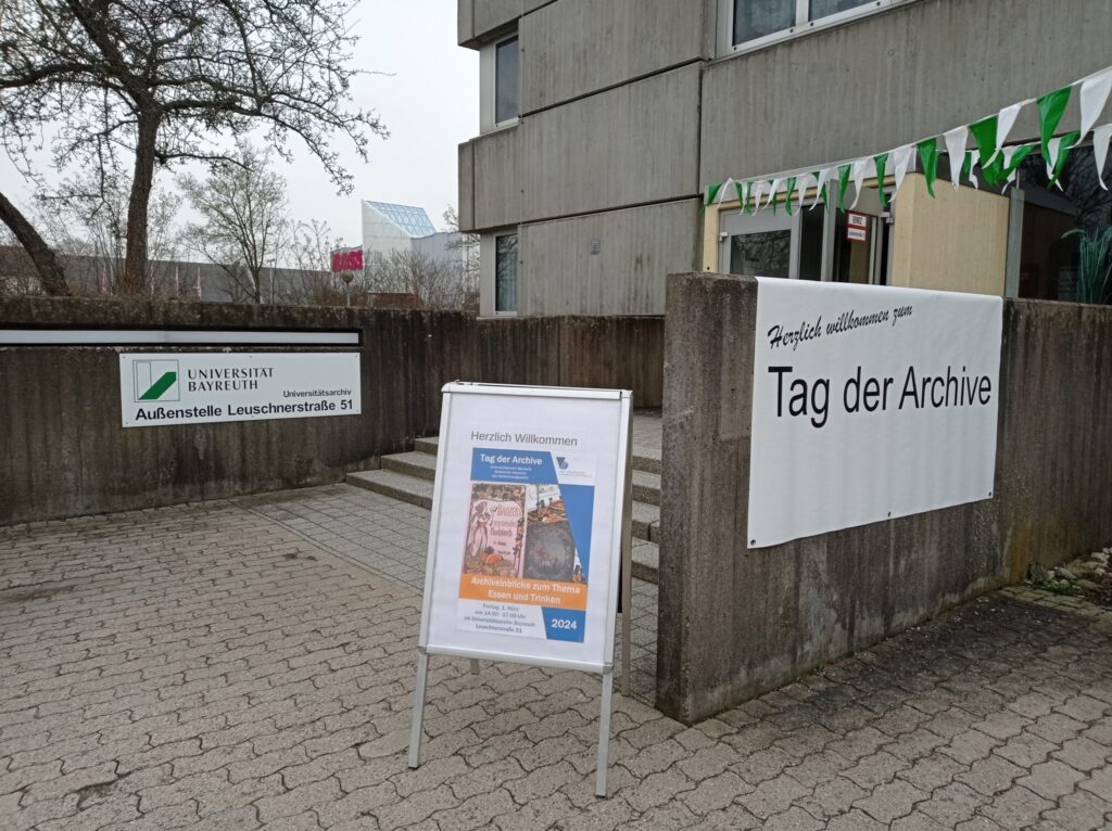 Blick auf den Eingang des Universiätsarchivs Bayreuth mit Plakataufsteller und Banner